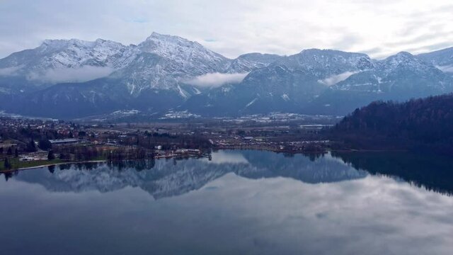 Drone aerial video footage above the Levico lake, facing the mountain Pizzo di Levico, with Forte Spitz Vezzena on the very top. Flying above the water