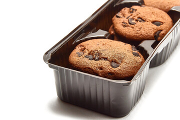 Delicious cookies with cocoa powder and droplets of chocolate icing in packaging on a white background.