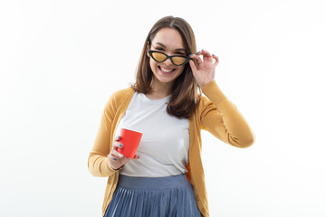 Young woman a yellow sweater drinks coffee from a red cup