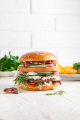 Fast food Burger. Close-up of tasty burger on a light wooden table and the background of a brick wall. Different type of sandwiches