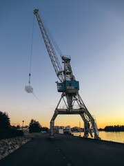 Old harbor crane at sunset.