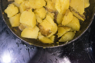 Fried potatoes. Cast-iron pan. Wooden spatula. Homemade food.