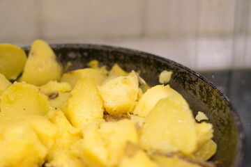 Fried potatoes. Cast-iron pan. Wooden spatula. Homemade food.