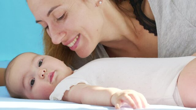 Close up mother gently kissing baby enjoying loving mom playfully caring for toddler at home sharing connection with her newborn child, healthy childcare.