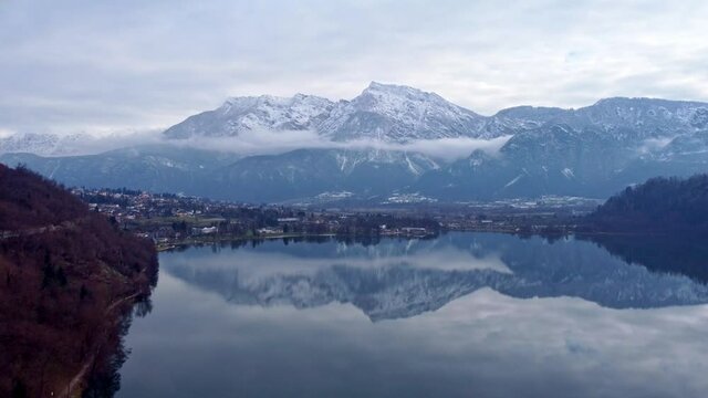 Drone aerial video footage above the Levico lake, facing the mountain Pizzo di Levico, with Forte Spitz Vezzena on the very top. Flying above the water
