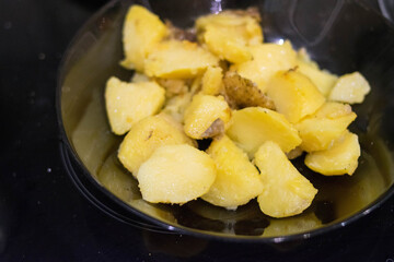 Fried potatoes. Glass plate. Wooden spatula. Homemade food.