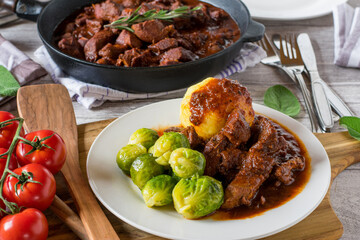 Goulash with brussels sprouts and potato dumplings on a plate