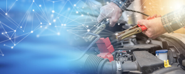 Hands of car mechanic using car battery jumper cable; panoramic banner