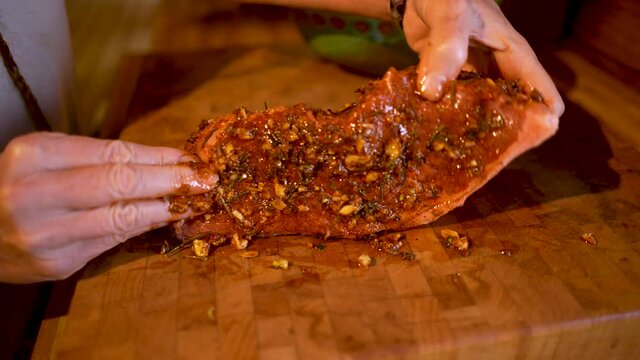 Woman rubbing spices and seasoning into a large piece of beef