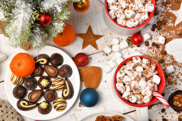 sweet food top view background for merry christmas or new year holiday decoration - chocolate candies, tangerines, cookies, marshmallow and cocoa latte on white wood