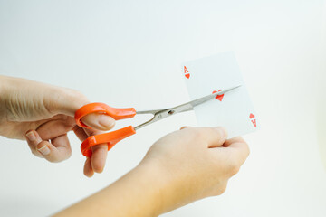 hands cutting the ace of hearts card with scissors