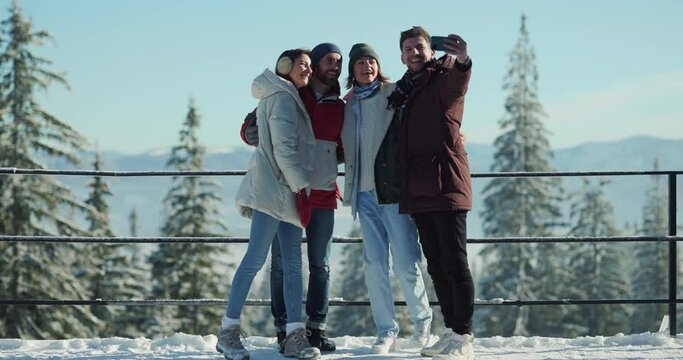 Attractive young diverse people taking common selfie photo picture on smartphone camera while staying at winter resort together. Best friends. Communication.