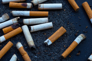 Cigarettes buds with ashtray on dark background.