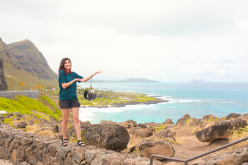Teen girl standing on stone wall arms stretched over ocean