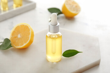Bottle with lemon essential oil on light background