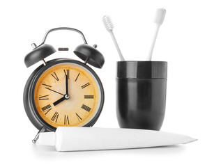 Alarm clock, paste and toothbrushes on white background