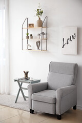 Soft armchair, table and shelf in interior of living room
