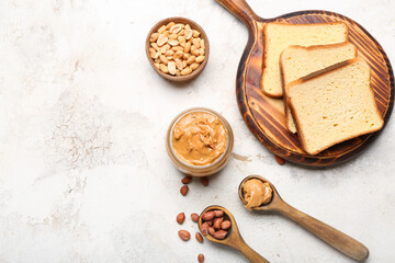Bowl with tasty peanut butter, nuts and toasts on table