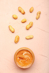 Bowl with tasty peanut butter and nuts on color table