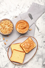 Bowl with tasty peanut butter, toasts and nuts on table