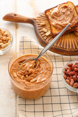 Bowl with tasty peanut butter and toasts on table