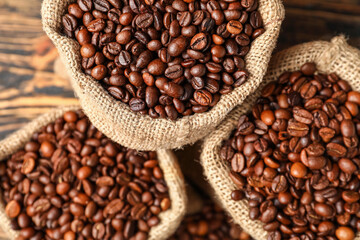 Bags with coffee beans on wooden background, closeup