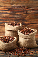 Bags with coffee beans on wooden background