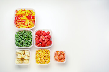 Plastic containers with different frozen vegetables on white background