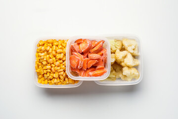 Plastic containers with different frozen vegetables on white background