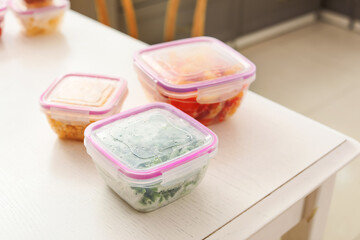 Plastic containers with frozen vegetables on table