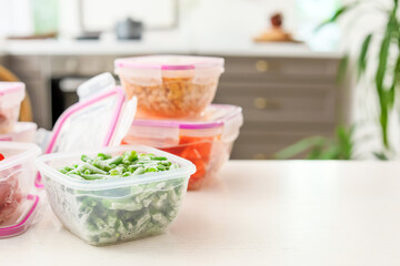 Plastic containers with frozen vegetables on table