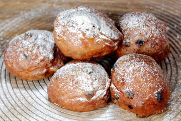 Dutch deep-fried raisins buns with powdered sugar and raisins on a wooden plate
