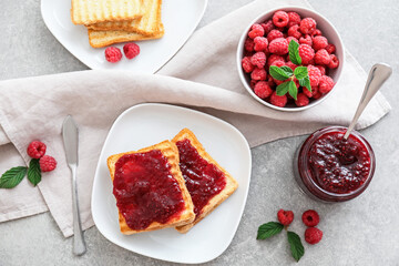 Toasts and jar with sweet raspberry jam on table