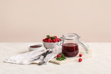 Jar with sweet raspberry jam on table