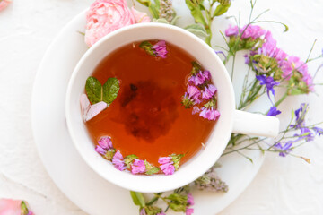 Cup with floral tea on light background