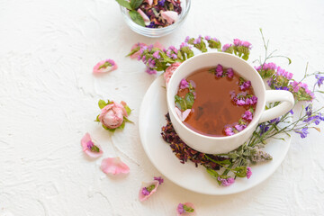 Cup with floral tea on light background