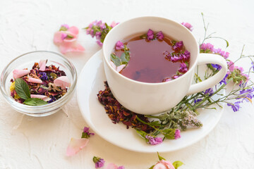 Cup with floral tea on light background