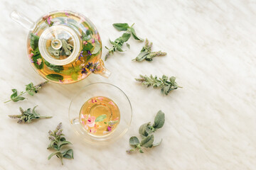 Teapot and cup with herbal tea on light background