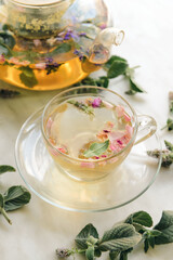 Teapot and cup with herbal tea on light background