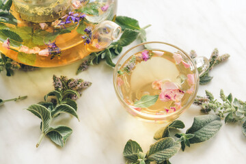 Teapot and cup with herbal tea on light background