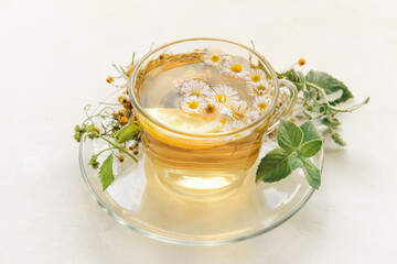 Cup with herbal tea on light background