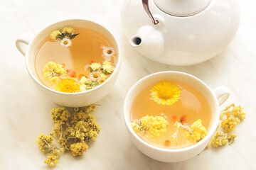 Teapot and cups with floral tea on light background