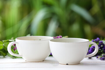 Cups with herbal tea and dry flowers on table against blurred background
