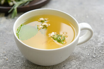 Cup with herbal tea on gray background