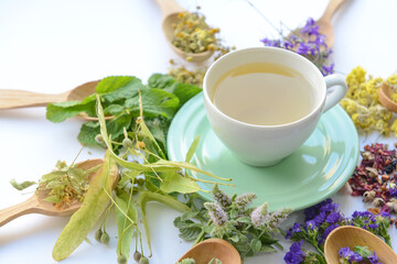 Dry flowers, spoons and cup with floral tea on light background