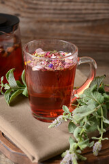 Teapot and cup with herbal tea on wooden background