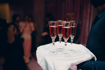 Glasses of rose sparkle wine on waiter hand dish