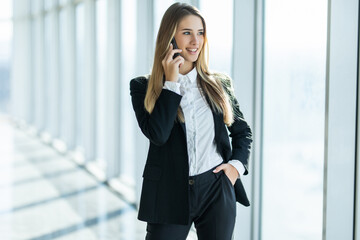 Smiling young business woman talking on phone in office