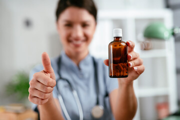 Beautiful female doctor working in the clinic. Beautiful nurse holding medicine pill and showing thumbs up.