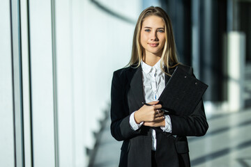 Portrait of young business woman with clipboard making notes in the office